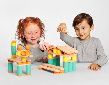 Two children creating two structures from colorful silicone and wooden figures