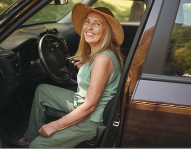 Mujer mayor sonriendo mientras se sube a su coche, reflejando independencia y autonomía en la tercer