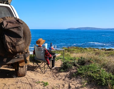 Toeristen genieten van hun kamping plekje aan het water met een 4WD