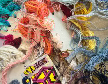 a bunch of yarn and threads of different colours tangled together