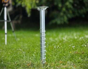 Galvanized steel ground screw anchor installed in a green lawn for deck and shed foundations.