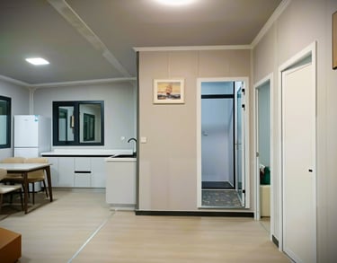Intérieur moderne avec cuisine équipée, coin repas et murs composites pour maison préfabriquée.