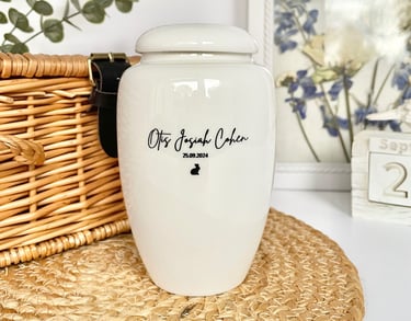 Glossy white ceramic urn with soft curves, black script engraving “Otis Josiah Cohen 25.09.2024” and