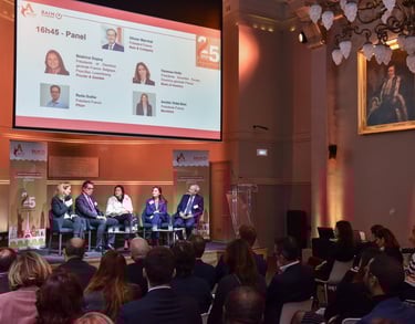 5 dirigeants d'entreprises sont sur scène lors d'une conférence, face à un public dans la pénombre.