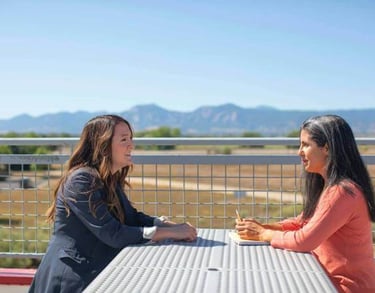 two women sitting at a table having a conversation