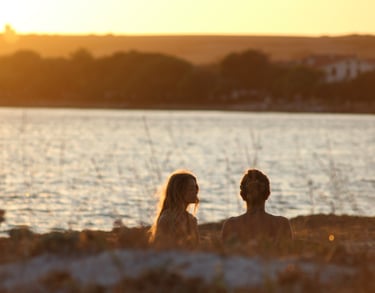 two people doing yoga on a beach with a sunset in the background