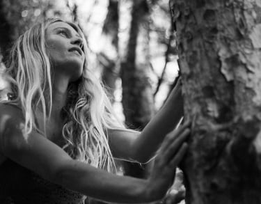 una donna in natura appoggiata ad un albero