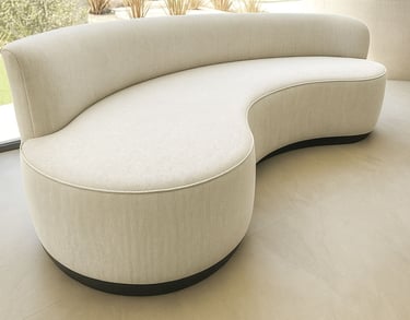 Curved light-gray upholstered sofa with textured fabric and black base in modern room with natural light — by Solo Home Decor