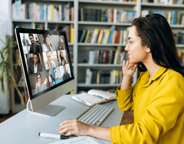 a woman sitting at a computer screen with a computer screen showing a video chat