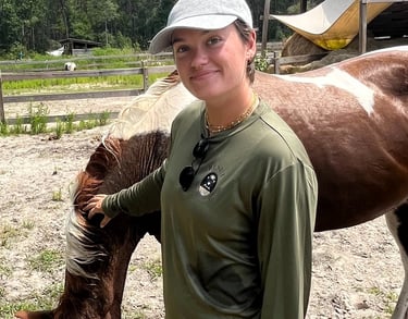 Sierra Sawtelle in a hat and a hat standing next to a horse