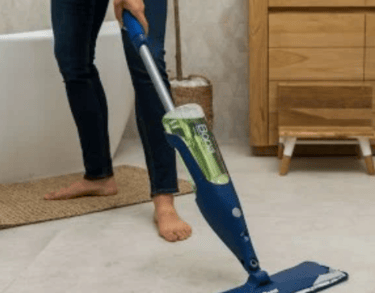 a woman is cleaning a tile floor with a mop