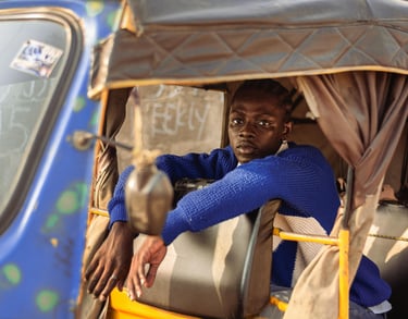 a man in a blue sweater sitting in a tuk tuk