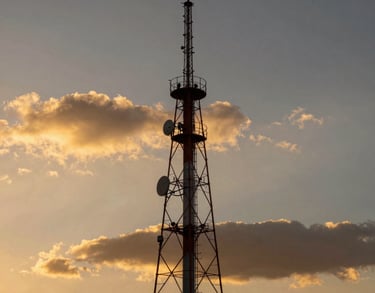 A scenic view of a radio tower against a dramatic Mexican sunset with golden and dark tones, symbolizing reach and power.