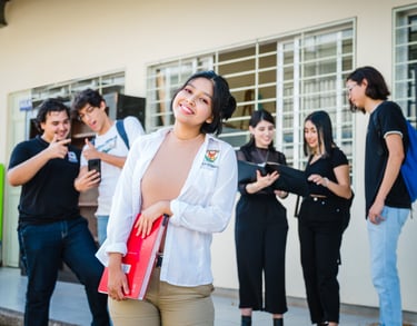 una estudiante sonriendo y detras hombres y mujeres estudiantes