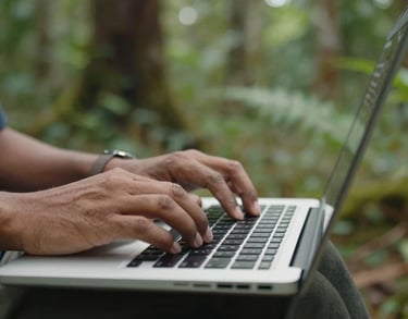 Close-up of a data specialist's hands using a laptop in the field, with an Indonesian forest in the blurred background, representing data-driven conservation.