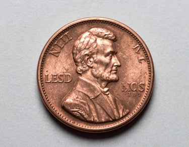 A macro photograph of a rare Lincoln penny showing incredible detail and copper luster, resting on a clean light grey surface. North American / US context.