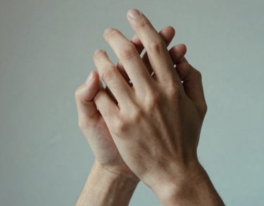 A close-up of two hands clasped together in a gesture of support, set against a background of soft grey and light aqua tones, North American / US context.