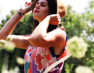 photo jeune femme en robe fleurie avec un chapeau au milieu d'un champs