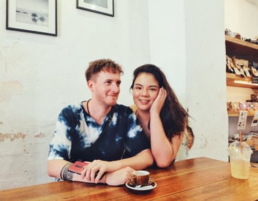 A happy young couple sitting together at a wooden table in a cozy cafe enjoying coffee.