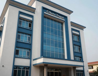 A clean, architectural photograph of the trust's headquarters in Chhotaudepur. The building features modern Indian design with elegant blue accents and large windows reflecting the South Asian sky.