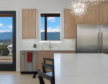 Modern kitchen featuring wood cabinets, stainless steel appliances, and a marble backsplash with mountain views.