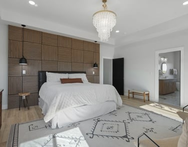 Modern bedroom featuring a wood slat accent wall, white bedding, and a luxury crystal chandelier.