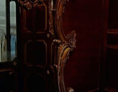 Ornate gilded baroque mirror with cherub carvings and gold acanthus scrollwork against deep crimson