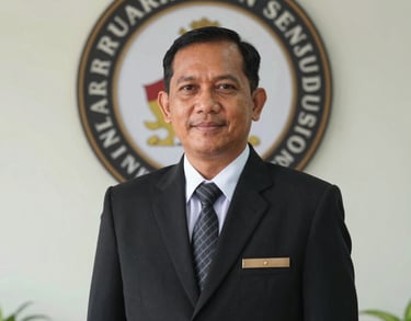 Professional portrait of a male Indonesian school principal in formal attire, standing in front of the school's logo, professional and welcoming expression.