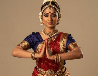Professional studio portrait of a female South Asian / Indian classical dancer in traditional bharatanatyam attire, holding a graceful mudra, soft warm beige lighting, premium artistic style.