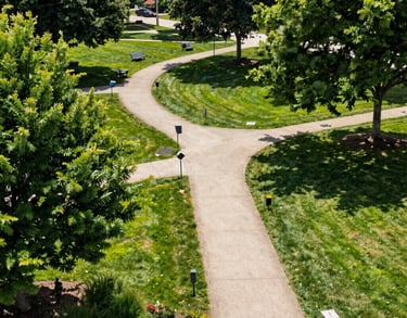Professional high-angle shot of a lush community park in the US with well-maintained paths and greenery, symbolizing stability and community well-being under bright, natural daylight.