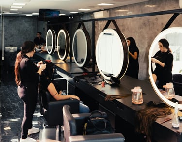 Estilistas profesionales trabajando en estaciones modernas de salón con espejos