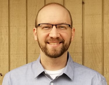 a man with a beard and glasses on a wooden wall