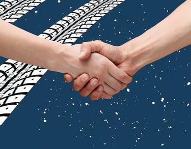 Dos manos de diferentes tonos de piel dándose un apretón de manos en el centro de un fondo azul con dos huellas de neumáticos