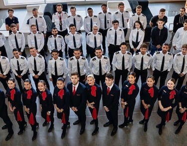 Diverse group of aviation students in uniforms reviewing flight plans in a classroom