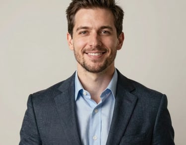 A studio portrait of a male professional in the North American philanthropic sector, dressed in business casual attire with a warm, confident expression. Neutral off-white background with soft, elegant lighting.