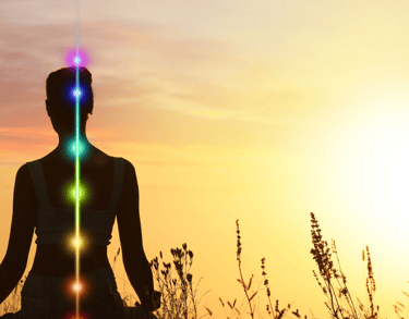Silhouette of a woman practicing yoga at sunset with seven glowing chakra symbols aligned along her spine.