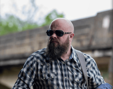 a man with a beard and sunglasses on a guitar