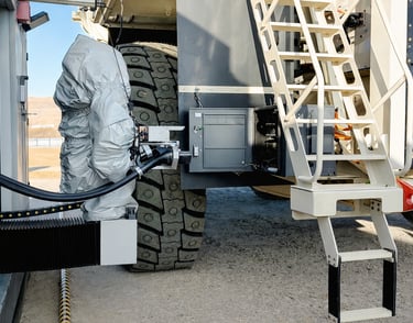Automated robotic charging system connecting to a large mining truck's charging port at a work site.