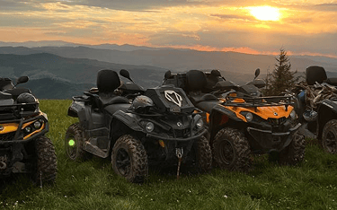 a group of four wheeler quad atvs parked on a grassy hill