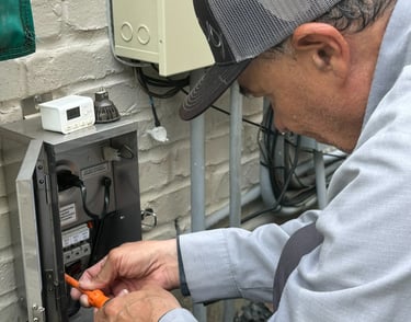 Electrician installing a professional low voltage landscape lighting transformer on an exterior wall.