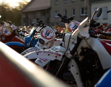 Close-up of vintage enduro motorcycles lined up for a classic off-road race at sunset.
