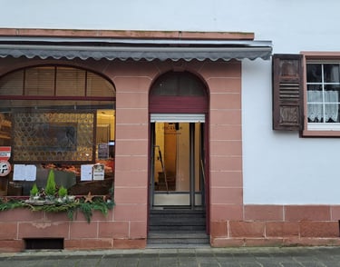 Fassade eines Metzgereigeschäfts mit Ladenschild, Schaufensterdekoration und Eingangstür