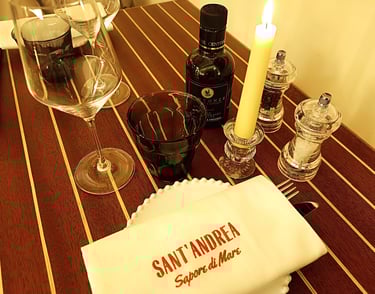 Tavolo apparecchiato al ristorante Sant’Andrea con tovagliolo ricamato e bottiglia di olio Centonze