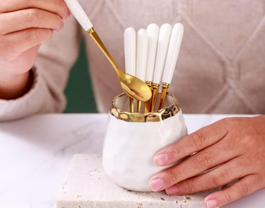 a woman's hands holding a gold spoon and spoons
