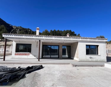 Villa moderne blanche récemment construite, avec baies vitrées coulissantes sous un ciel bleu dégagé