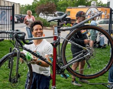 Smiling young man washing a bike with a sponge