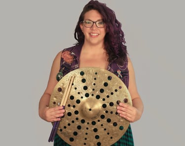 Rachel holding a cymbal with holes through out it, smiling 