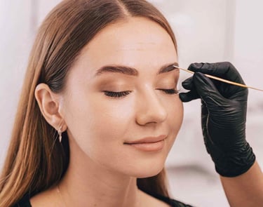 a woman is getting her eyebrows done by a professional makeup artist
