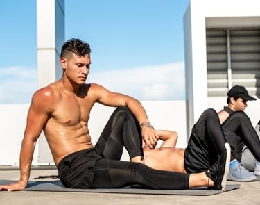 Athletic shirtless man performing core strengthening exercises on a yoga mat during an outdoor fitness class.