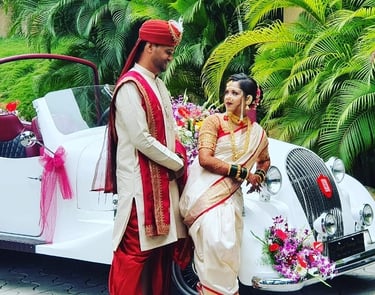 a man and woman in traditional indian attire standing in front of a car